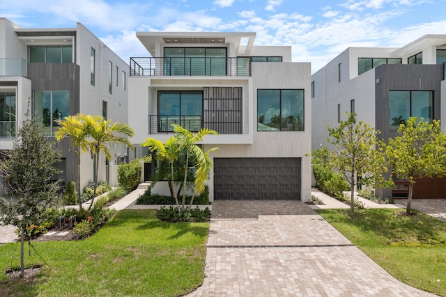 contemporary house featuring decorative driveway, an attached garage, and stucco siding