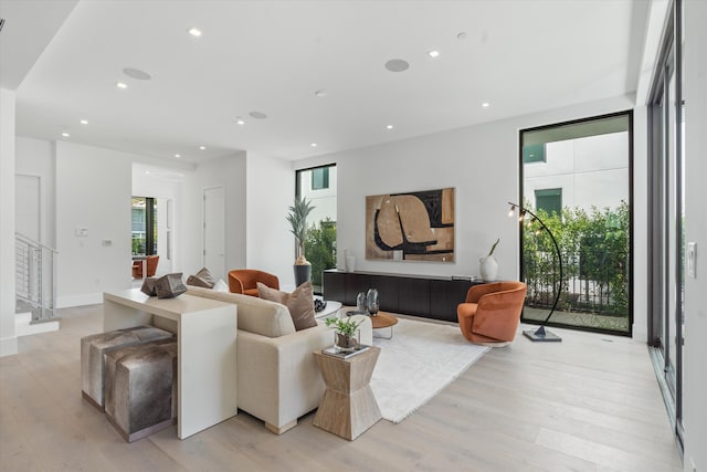 living area featuring light wood-type flooring, baseboards, recessed lighting, and stairs