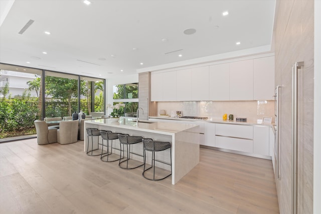 kitchen featuring a sink, visible vents, tasteful backsplash, modern cabinets, and a kitchen bar