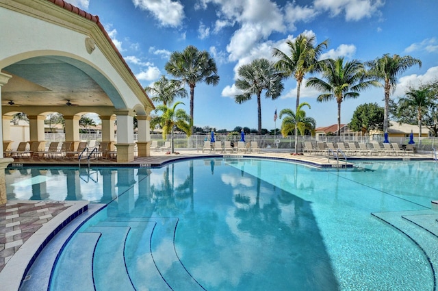 community pool with ceiling fan, a patio area, and fence