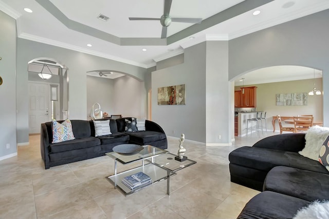 living area featuring baseboards, arched walkways, a raised ceiling, and a ceiling fan