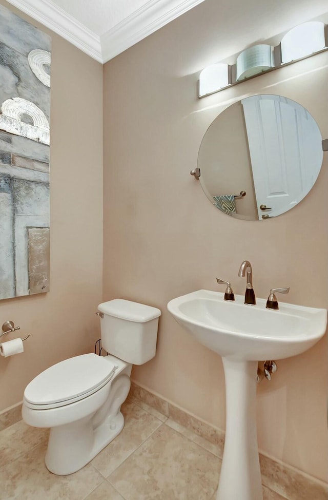 half bath featuring toilet, baseboards, crown molding, and tile patterned floors