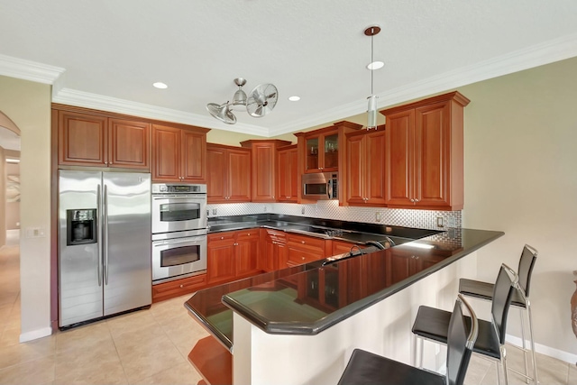 kitchen featuring tasteful backsplash, a breakfast bar area, appliances with stainless steel finishes, a peninsula, and a sink