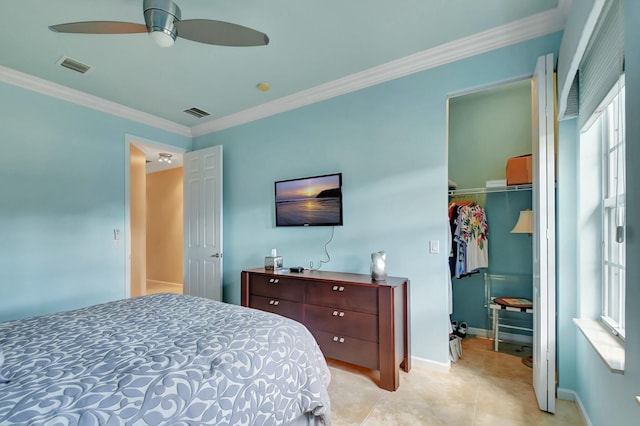 bedroom with a walk in closet, a closet, visible vents, and crown molding