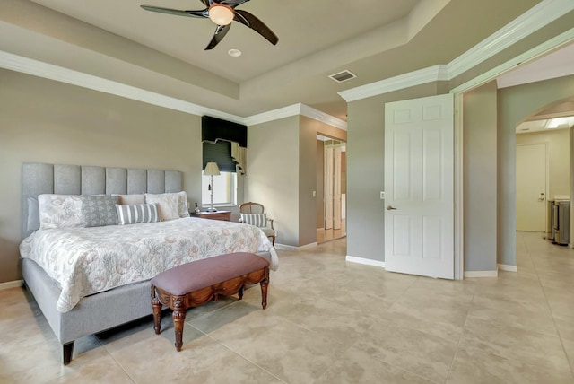 bedroom with a tray ceiling, visible vents, arched walkways, and baseboards