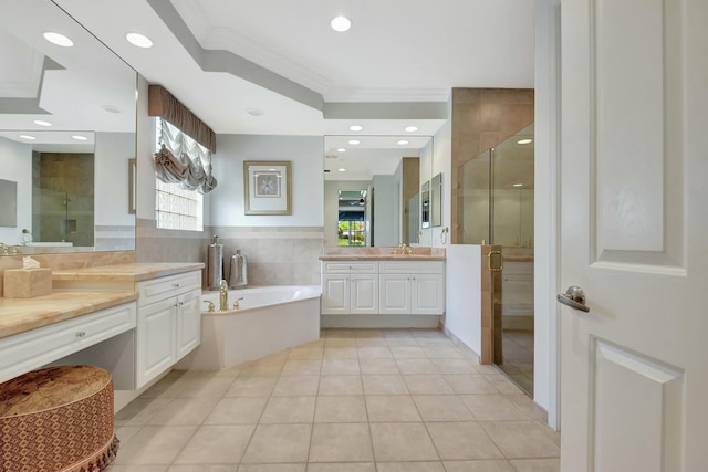 bathroom featuring a garden tub, two vanities, ornamental molding, tile patterned floors, and a stall shower