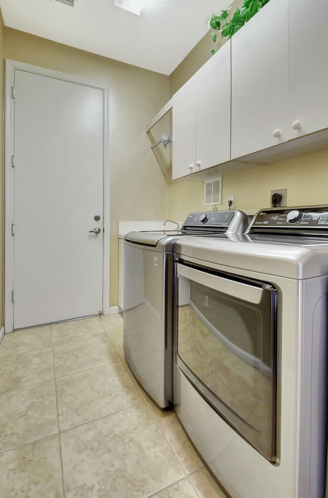 clothes washing area featuring visible vents, light tile patterned floors, independent washer and dryer, and cabinet space