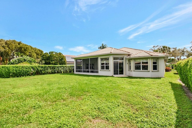 back of property featuring a yard, a tiled roof, and a sunroom