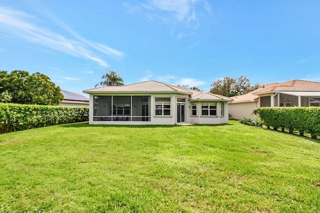 rear view of house with a sunroom, a tile roof, and a yard