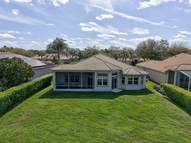 rear view of property featuring a sunroom, a tiled roof, stucco siding, and a yard