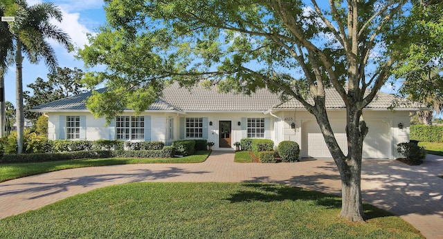 view of front of property featuring a garage, a front yard, decorative driveway, and a tile roof