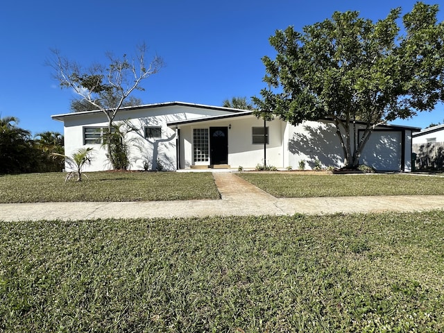 view of front facade with an attached garage, a front yard, and stucco siding