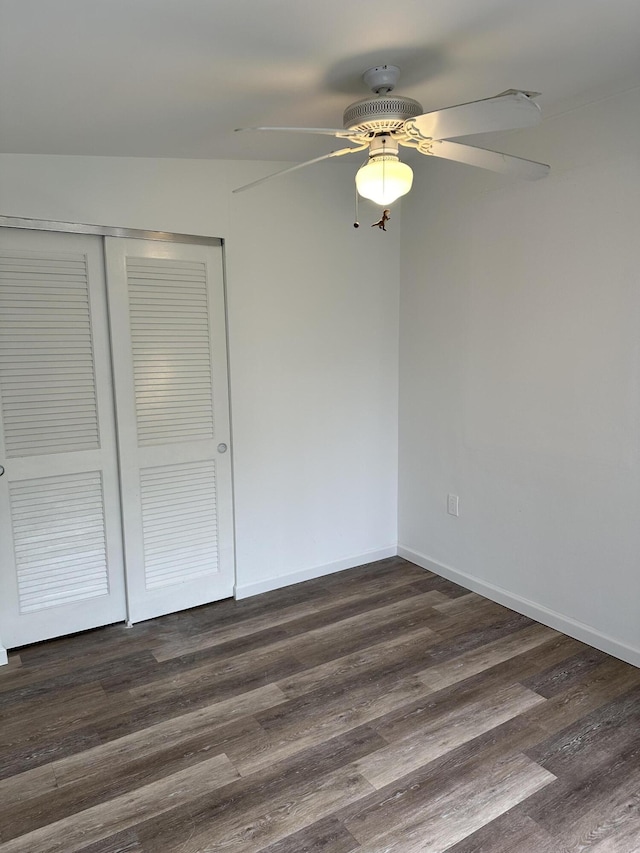 unfurnished bedroom featuring dark wood-style floors, ceiling fan, a closet, and baseboards