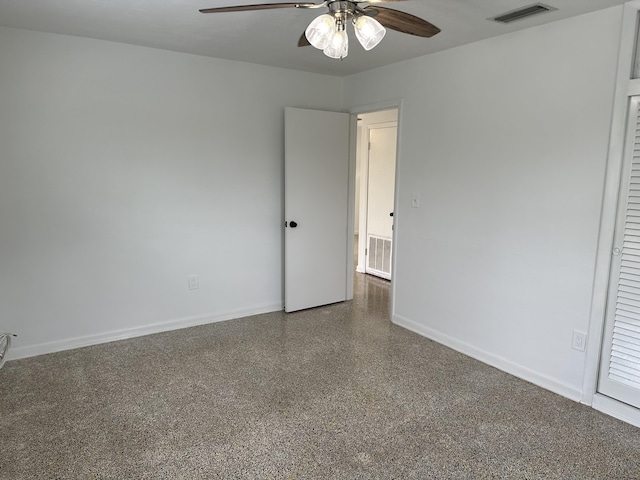 spare room featuring baseboards, speckled floor, visible vents, and a ceiling fan