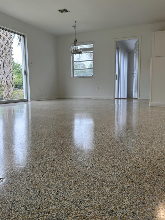 spare room with baseboards, visible vents, a chandelier, and speckled floor