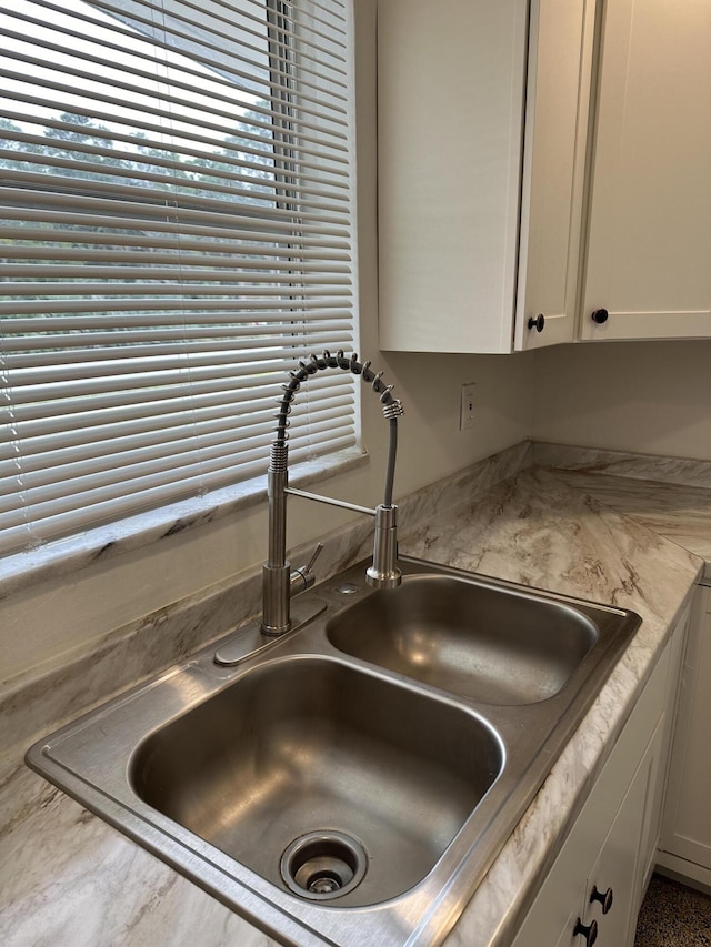 interior details with light countertops, a sink, and white cabinetry