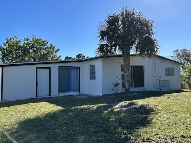 back of property featuring stucco siding and a yard