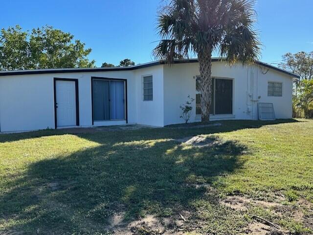 back of property with a lawn and stucco siding