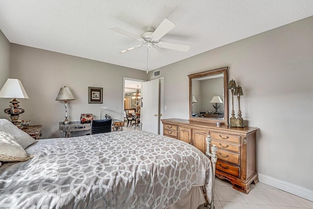 bedroom featuring a textured ceiling, light tile patterned floors, ceiling fan with notable chandelier, visible vents, and baseboards