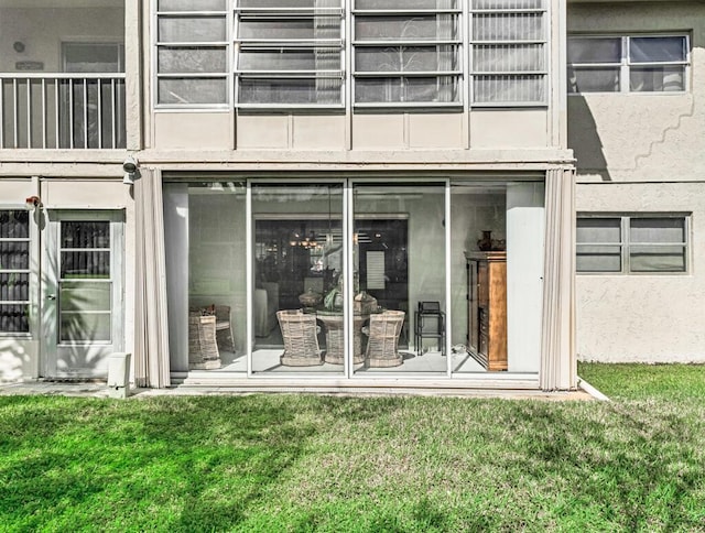 property entrance with a lawn and stucco siding