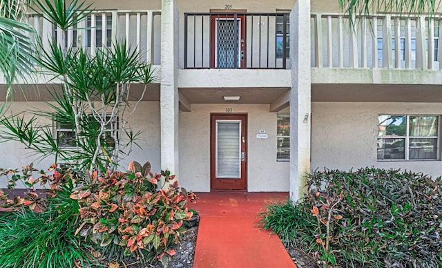 property entrance featuring a balcony and stucco siding