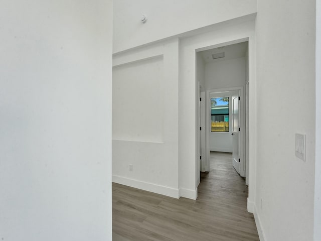 hall with baseboards and light wood finished floors