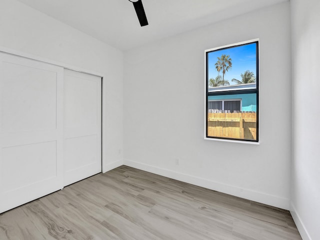 unfurnished bedroom with a ceiling fan, light wood-style flooring, baseboards, and a closet