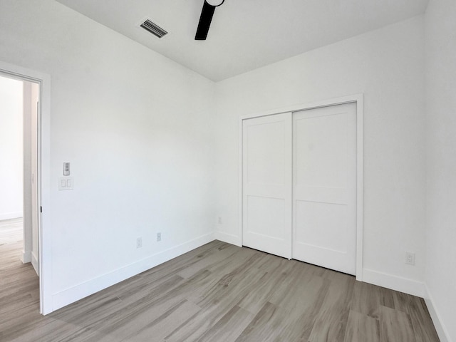 unfurnished bedroom with light wood finished floors, baseboards, visible vents, and a closet