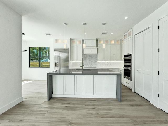 kitchen with stainless steel appliances, dark countertops, glass insert cabinets, and white cabinets