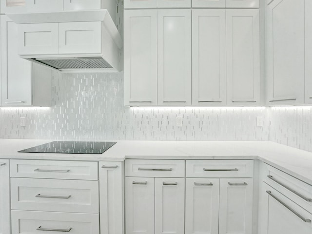 kitchen with custom exhaust hood, light countertops, decorative backsplash, white cabinets, and black electric cooktop