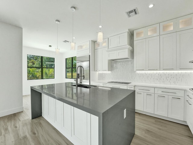 kitchen with black electric cooktop, a center island with sink, glass insert cabinets, and white cabinets