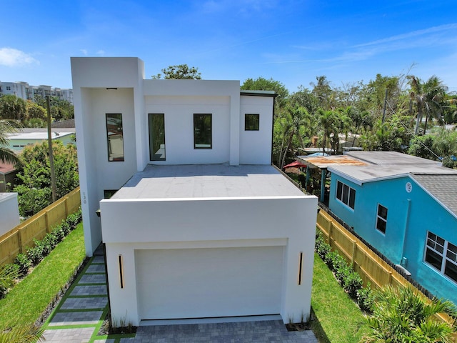 view of front facade featuring a garage, decorative driveway, fence, and stucco siding