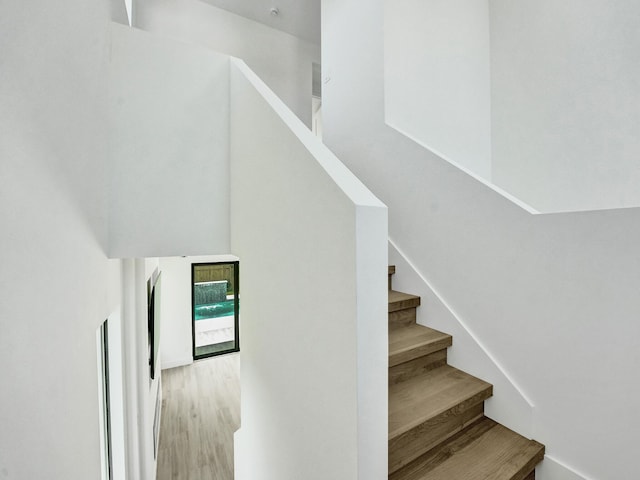 stairway featuring wood finished floors and a towering ceiling