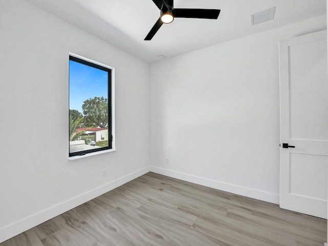 unfurnished room featuring light wood finished floors, a ceiling fan, visible vents, and baseboards