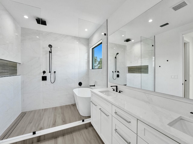 full bathroom with a freestanding bath, a sink, and visible vents