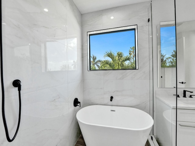 bathroom featuring a freestanding tub, vanity, and tile walls