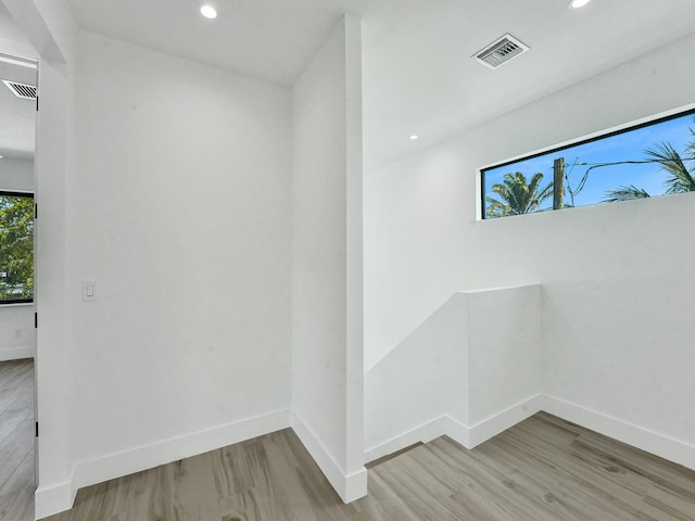 corridor with baseboards, visible vents, and light wood finished floors