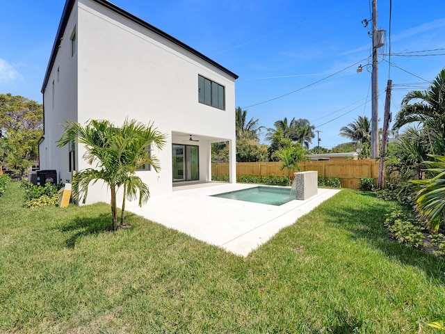 rear view of house with a lawn, a patio area, fence, and stucco siding