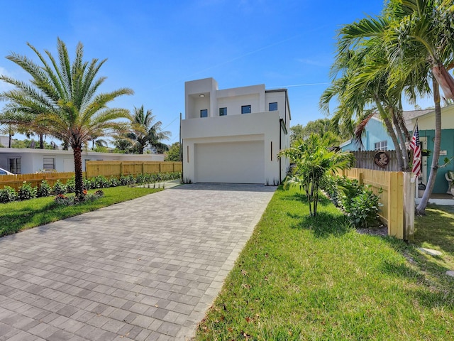 view of front of house featuring a garage, fence, a front lawn, and stucco siding