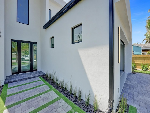 exterior space featuring fence, french doors, and stucco siding