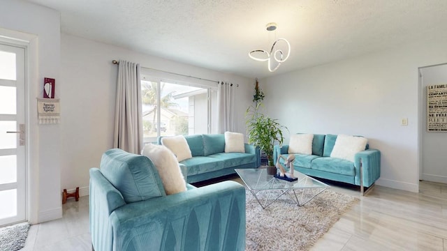 living room featuring a textured ceiling, baseboards, and a notable chandelier