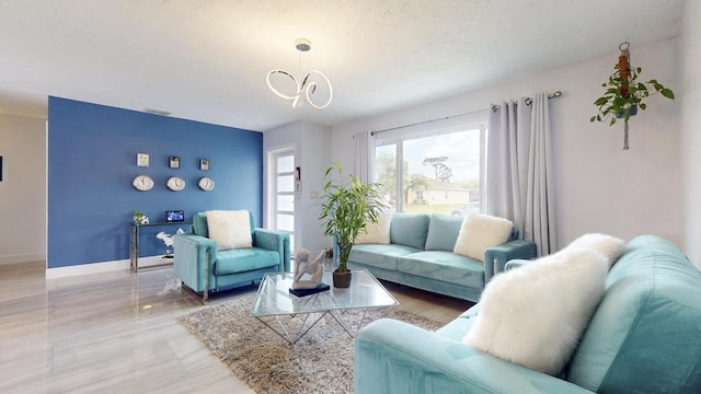 living area with baseboards, a chandelier, and a textured ceiling