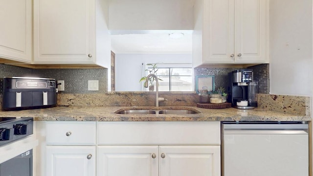 kitchen with dishwashing machine, a sink, and white cabinets