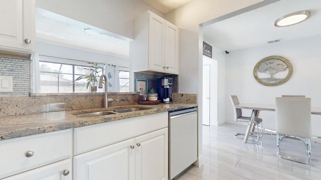 kitchen with stone countertops, visible vents, stainless steel dishwasher, white cabinetry, and a sink