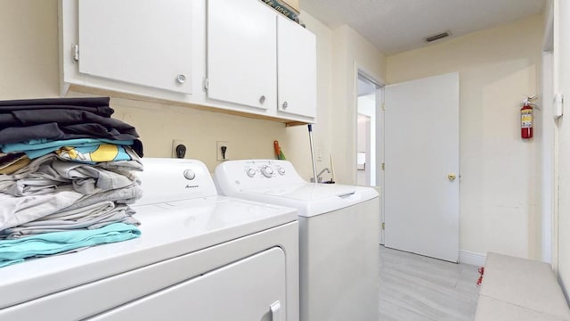 laundry room featuring washing machine and dryer, visible vents, and cabinet space