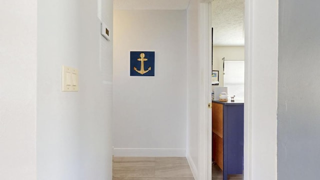 hallway featuring baseboards and a textured ceiling