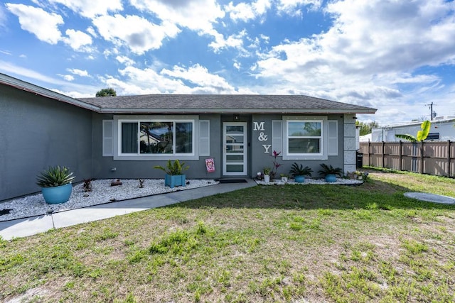 view of front of property featuring a front yard, fence, and stucco siding