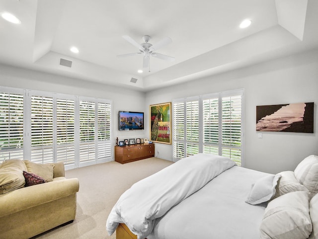 bedroom featuring light carpet, a tray ceiling, and recessed lighting