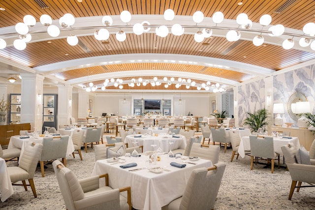 dining room with lofted ceiling, a chandelier, and ornate columns