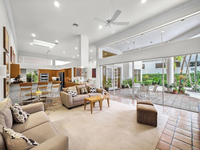 living area with a healthy amount of sunlight, visible vents, a high ceiling, and light tile patterned flooring